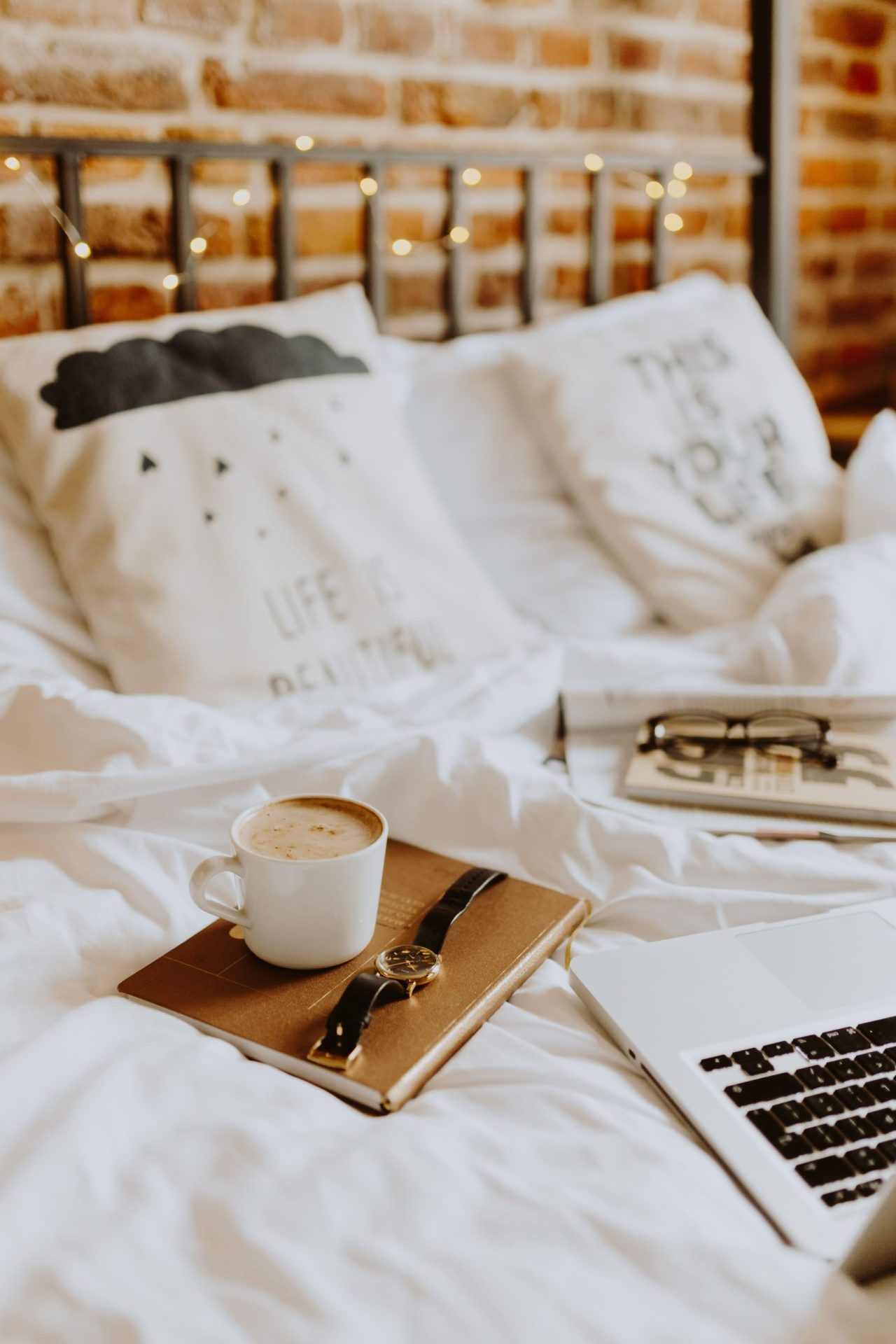 Bad Credit Mortgages | Image of a bed with a red brick back wall, metal frame, white bed sheets and a journal with a coffee on top