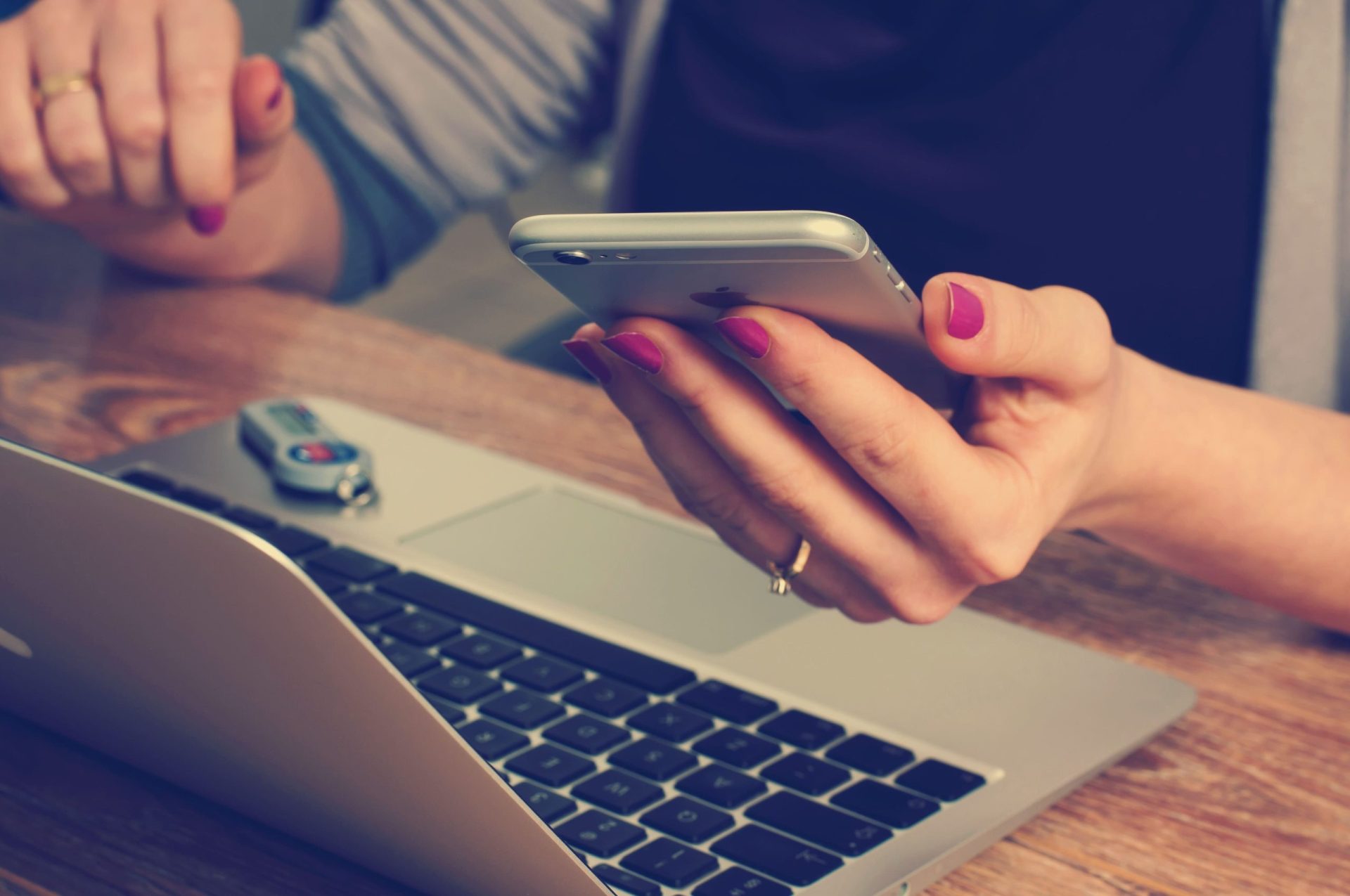 Bad Credit Bridging Loans | A lady sitting at a desk with pink nails holding her phone at a laptop