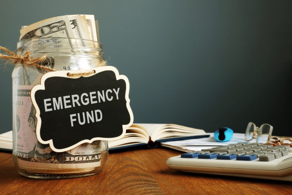 Glass jar with money in it with a sign that says emergency fund