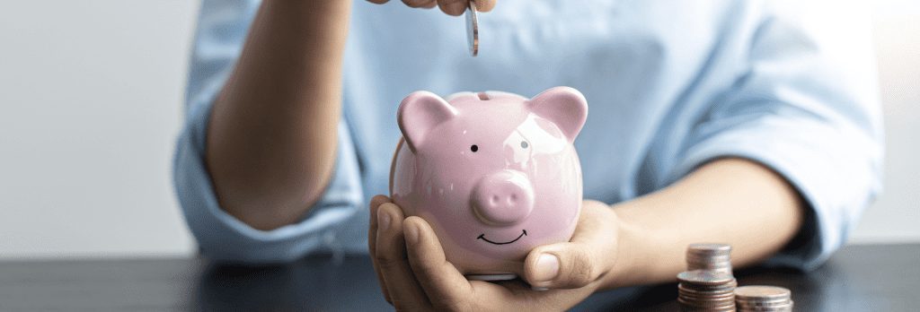 Gifted Deposits | A person holding a pink piggy bank in their palm, adding coins into the bank