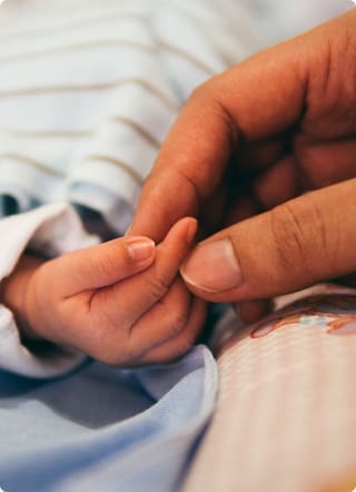 Income protection | Hand holding a newborn baby's hand