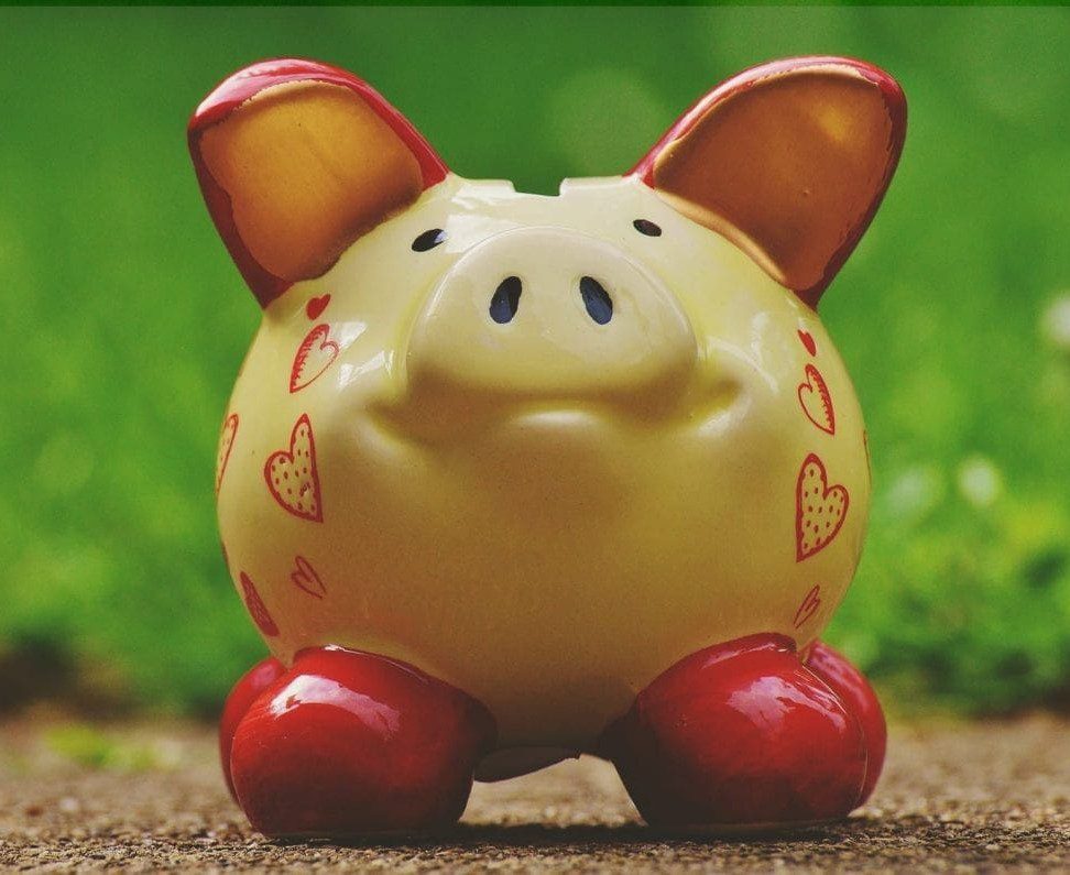 Monthly Payments | Bright yellow piggy bank with red feet and ears and red love hearts on the sides.