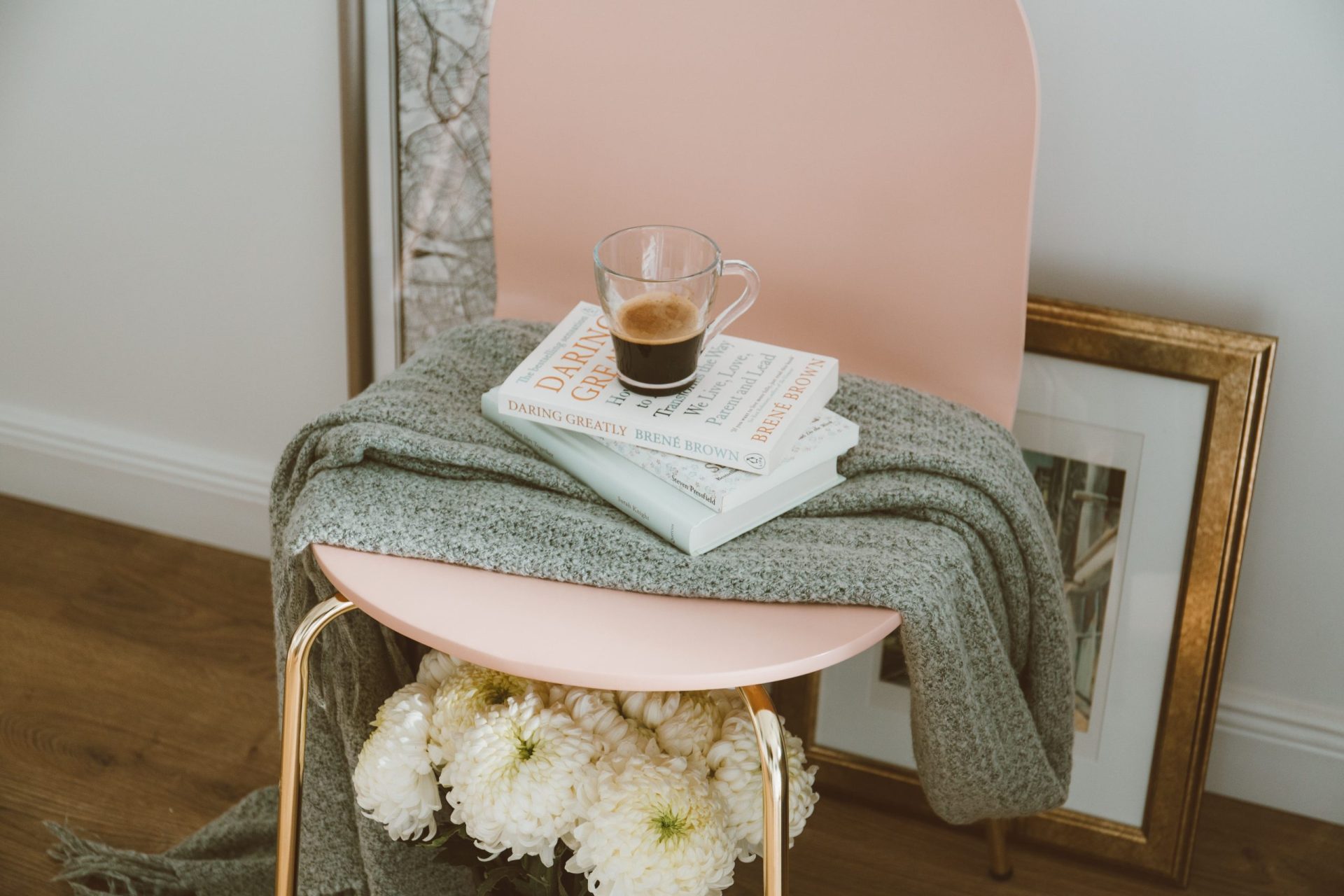 Getting a mortgage after repossession | A pale pink chair with a throw, books and a coffee on top and artwork in a gold frame on the floor behind, leaning against the wall