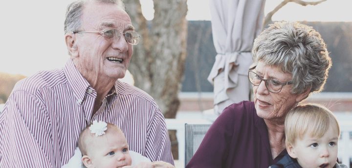 Two grandparents holding their two grandchildren