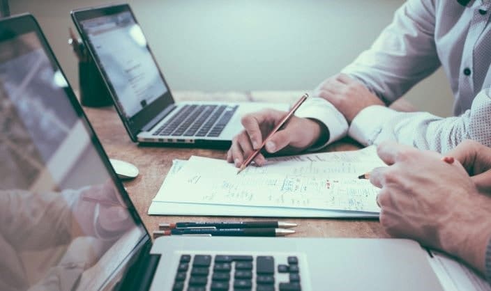 Widget Contractors | Two people sitting at a table with laptops and paperwork