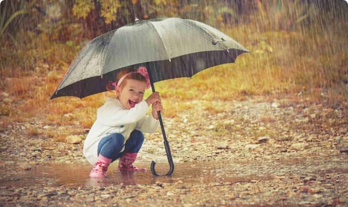 Widget Insurance | Child playing in the rain in wellies under an umbrella